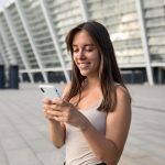 mujer mirando el celular en el exterior de un edificio
