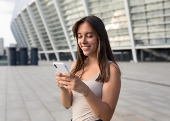 mujer mirando el celular en el exterior de un edificio