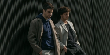 dos personas paradas contra una pared