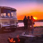 trailer en atardecer y tres chicas paradas al costado
