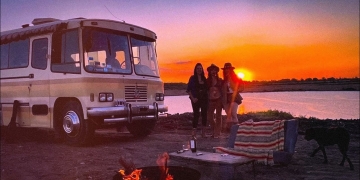 trailer en atardecer y tres chicas paradas al costado